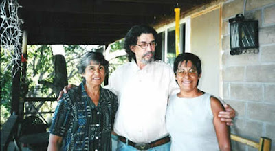 Xuy Leyba with two women, arms around each other, outdoors